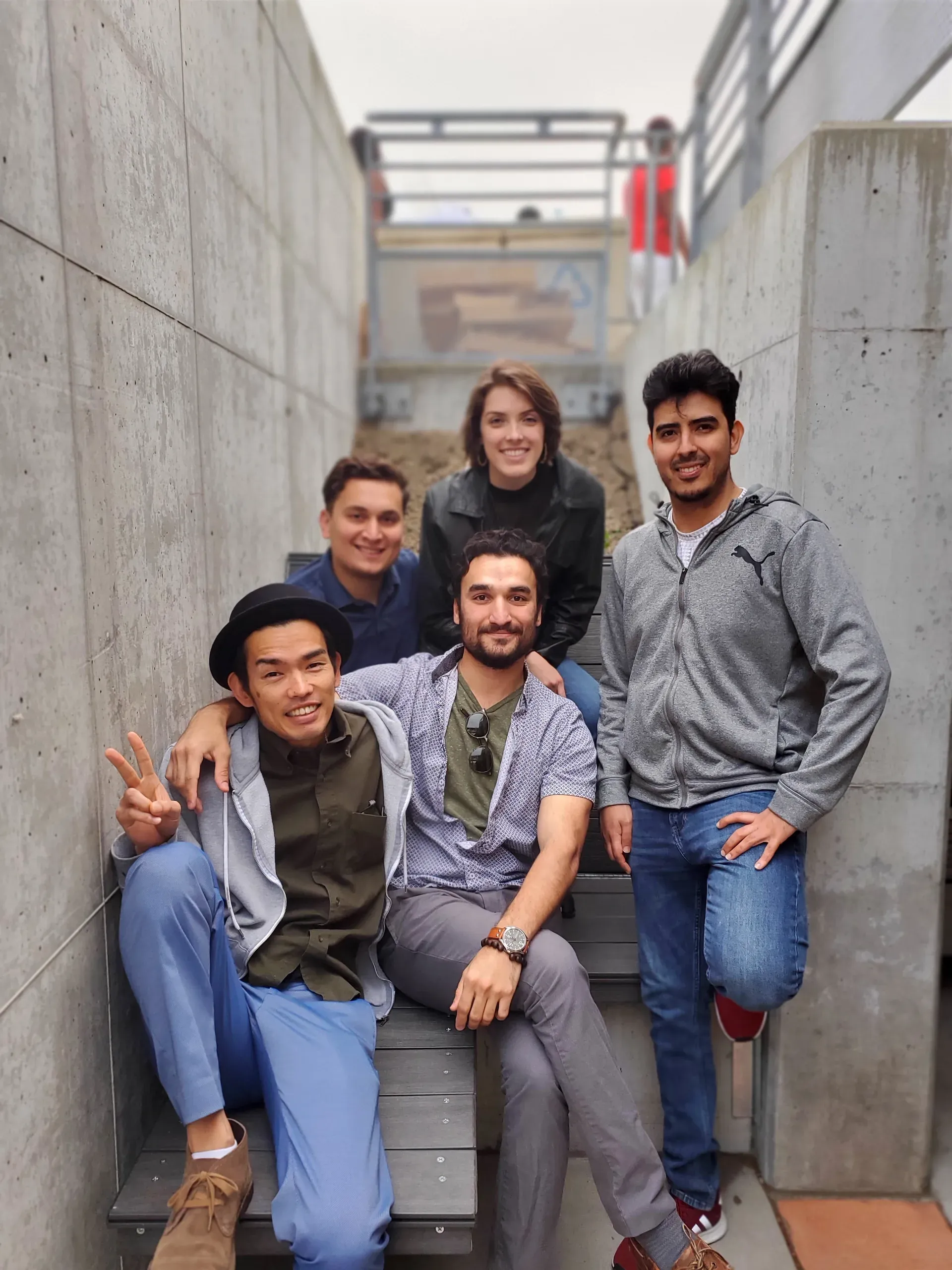 Five students on the finished bench in the pocket between the concrete walls, three seated on the deck and two standing either side